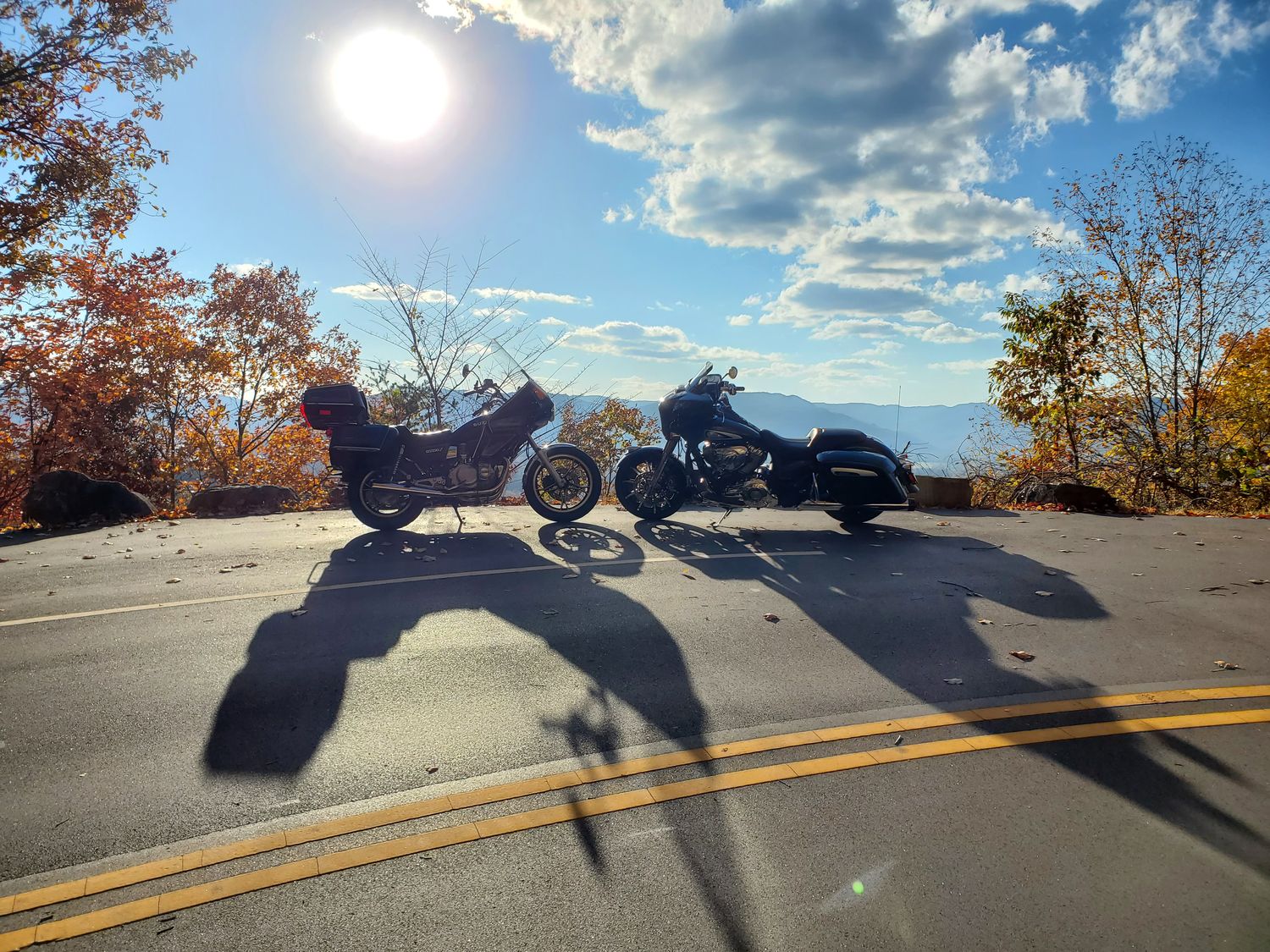 Two motorcycles at a mountain overlook in autumn